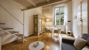 Una habitación con escalera, comedor, sofá y ventana con cortinas.