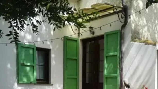 A patio with a round table and four chairs, a small potted plant, and a green door. - Room 'Camera D'ambra' with Private Terrace, Private Garden and Wi-Fi (Campiglia Marittima)