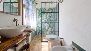 A bathroom with a wooden vanity, a white sink, a toilet, a shower with a glass door, and a mirror. - 'La Stanza di Campagna' with Shared Garden and Wi-Fi (Campiglia Marittima)