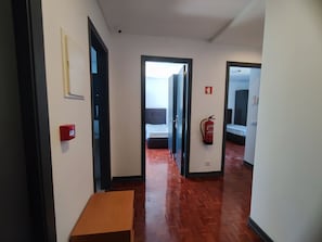 Un couloir doté d’un plancher en bois, d’un extincteur et d’une boîte rouge contenant du matériel de premiers secours.