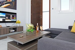 A modern living room with a flat-screen TV, a wooden coffee table, a sofa, and a decorative vase with flowers. - Villa Eva-Family with Pool In Kapparis Protaras (Paralimni)