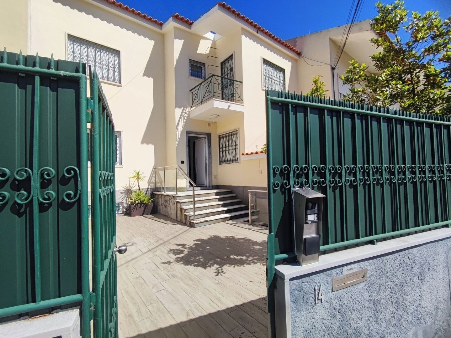 A building with a gated entrance, a staircase leading to a second floor, and a mailbox.