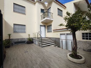 A multi-story building with a central staircase, potted plants, and a tiled patio area.