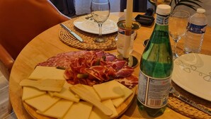 A dining table with a plate of cheese and cured meats, a bottle of water, and a candle. - Luxury suite with private Jacuzzi and garden 20 minutes from Paris NetFlix (Saint-Prix)