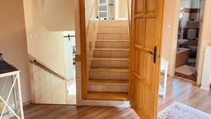 Una escalera con escalones de madera y una puerta blanca que da a un baño.