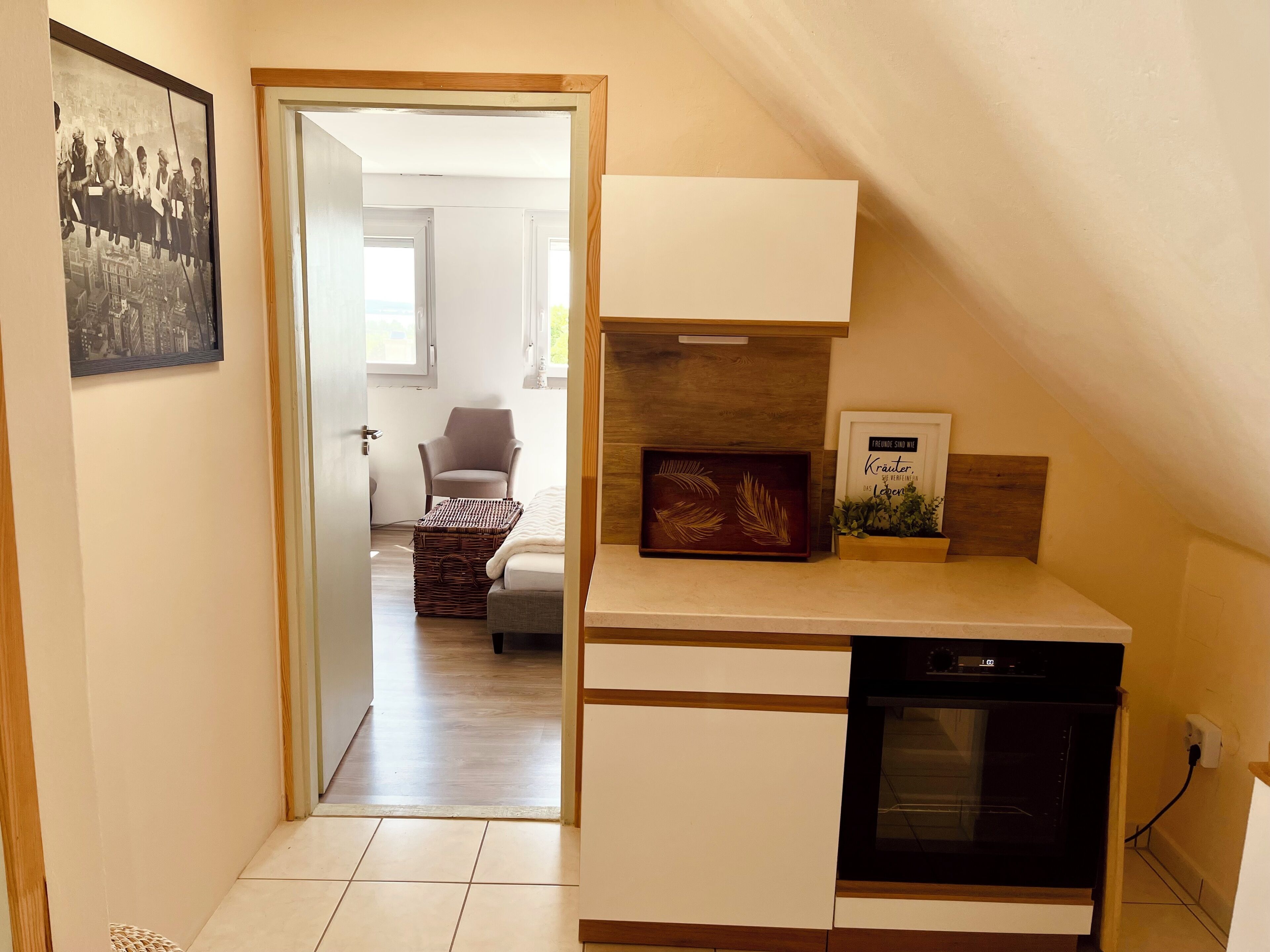 Une cuisine compacte dotée d’un four encastré, d’un petit coin repas avec une chaise et d’un tableau encadré au mur.