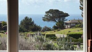 A coastal view from a window, including a large tree, a house, and the sea. - Irish Beach | Ocean Views, Hot-tub, Beach Access (Manchester)