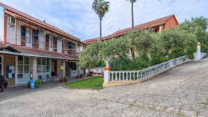 Un edificio con tetto in tegole rosse, un balcone con ringhiera bianca e un'area pavimentata con recinzione bianca.