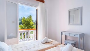 Una camera d'albergo con balcone, un letto, un comodino e uno specchio.