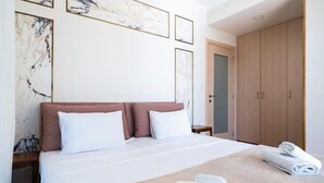 Ein ordentlich bezogenes Bett mit weißer und rosa Bettwäsche, ein Holzschrank und Marmorbildkunst an der Wand.