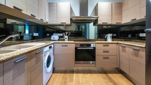Eine moderne Küche mit Holzausstattung, Edelstahlgeräten, einer integrierten Waschmaschine und einer großen Kücheninsel mit Spüle.