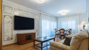 Ein Wohnzimmer mit Flachbildfernseher, Holzmöbeln und Marmorbildkunst.