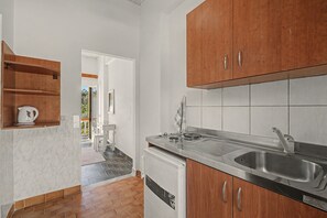 Eine Küche mit Holzschränken, einer Edelstahlspüle und einer weißen Arbeitsplatte.