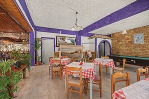 Ein Restaurant mit Holztischen und -stühlen, einer Billardkugel und einem Barbereich.