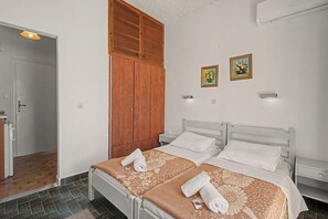 Ein Hotelzimmer mit zwei Betten, einem Kleiderschrank, einer Dusche sowie zwei an der Wand befestigten Bildern.