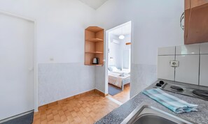 A compact kitchen with a built-in oven, a sink, and a wooden shelf. - Studio Apartment 'Maltas 6' with Shared Terrace, Wi-Fi and Air Conditioning (Corfu)