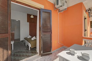 Ein Zimmer mit einem Bett, einem Tisch mit Tassen und einem Wandventilator.