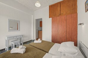 A bedroom with a bed, a bedside table, a mirror, a wooden wardrobe, and a bathroom visible through an open door. - Studio Apartment 'Maltas 6' with Shared Terrace, Wi-Fi and Air Conditioning (Corfu)