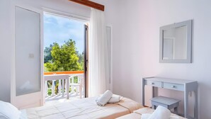 Ein Hotelzimmer mit Balkon, einem Bett, einem Nachttisch und einem Spiegel.