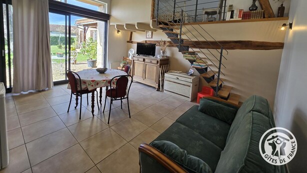 A cozy interior with a dining area, a sofa, a staircase, and a TV. - Charming lodging in Coursac - 2 guests (Coursac)