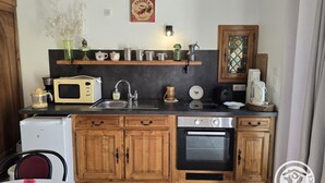 A compact kitchen with wooden cabinets, a microwave, a sink, and a coffee maker. - Charming lodging in Coursac - 2 guests (Coursac)