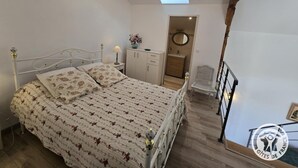 A bedroom with a bed, bedside table, lamp, and a small window. - Charming lodging in Coursac - 2 guests (Coursac)