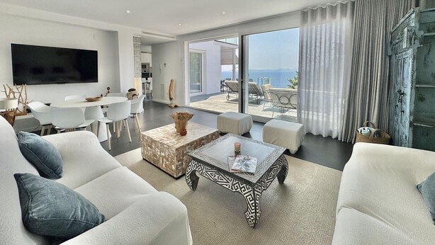 A modern living room with a large TV, white sofas, a patterned coffee table, and a view of the sea through large windows. - Villa Sol in Canyelles with private pool and Wi-Fi (Roses)