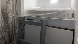 Ein kleines, separates Badezimmer mit Toilette, Spiegel und einer Leuchte darüber.