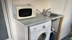 Ein kleiner Hauswirtschaftsraum mit einer Waschmaschine und einer darüber platzierten Mikrowelle.