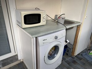 A compact laundry room with a washing machine and a microwave on top of it. - Apartment with AC, sea view - 4 guests (Hyères)