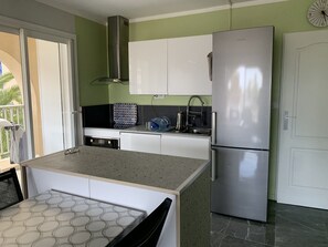 A compact kitchen with a stainless steel refrigerator, a microwave, and a kettle on the countertop. - Apartment with AC, sea view - 4 guests (Hyères)