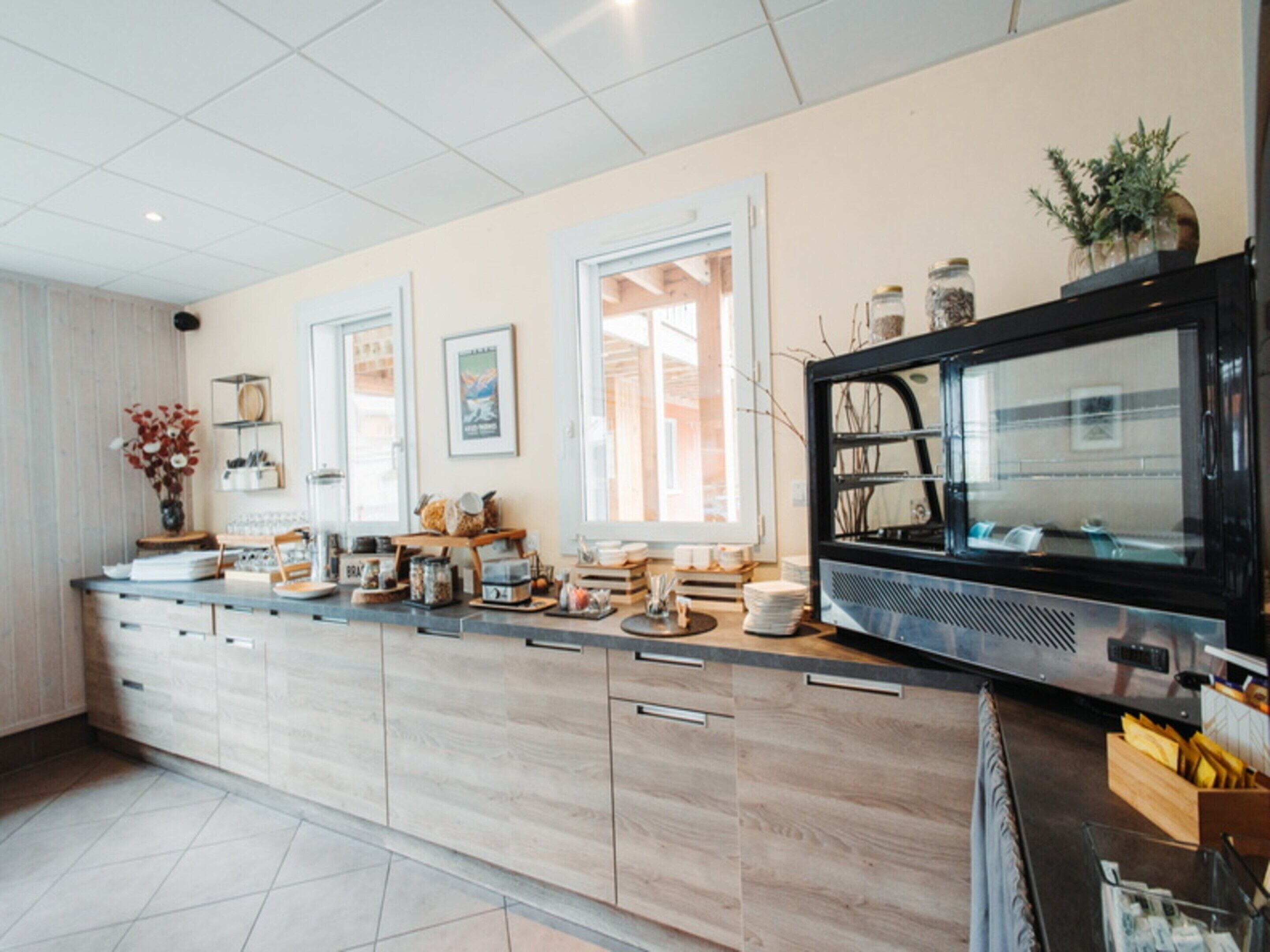 A modern kitchen with a large island, built-in cabinets, and a black refrigerator.