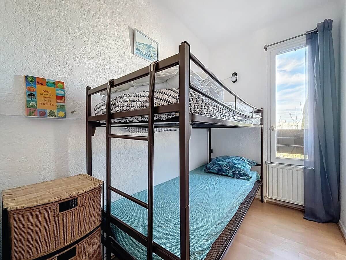A bunk bed room with a window, a wicker basket, and a wall-mounted picture.