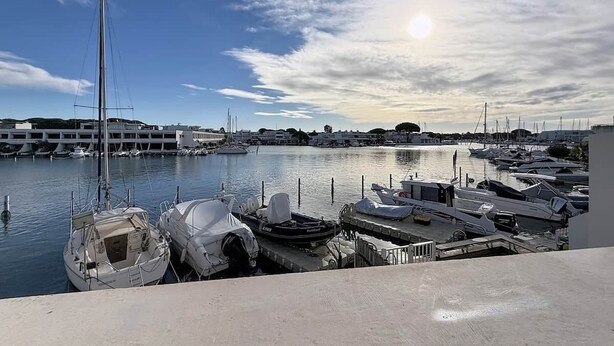 A marina with boats docked, a clear sky, and a building in the background. - Marina Saphirre-Port Ulysse -P2 (Le Grau-du-Roi)