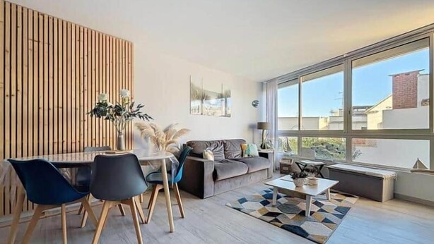 Ein modernes Wohnzimmer mit Essbereich, großen Fenstern und Blick auf die Stadt.