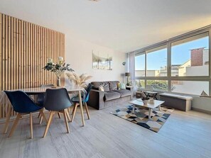 Una sala de estar moderna con comedor, ventanas amplias y vista a la ciudad.