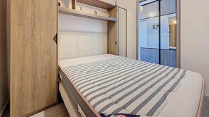 Ein kleines Schlafzimmer mit Bett, Einbauschrank und kleinem Fenster.