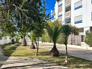 A pathway lined with palm trees and a building with balconies. - Sunny Blue Apartment in la Marsa (La Marsa)