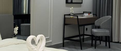 Une chambre d’hôtel avec un lit, un bureau et une chaise, ainsi qu’une œuvre d’art encadrée au mur.