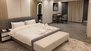 Una habitación de hotel moderna con una cama grande, una mesita de noche con teléfono, un escritorio con silla y un espejo.