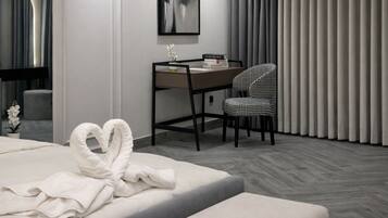 Una habitación de hotel moderna con una cama bien hecha, un escritorio con una silla y un ventanal con cortinas.