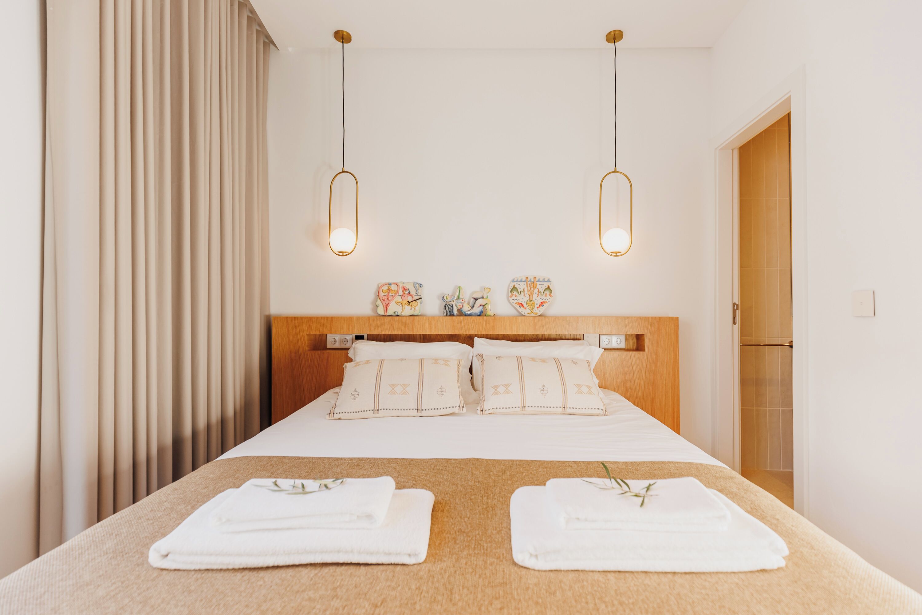 A hotel room with a bed, two bedside tables, a headboard, and a window with curtains.