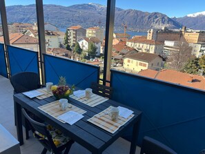 A balcony with a table set for two, overlooking a mountainous landscape and a town. - Zagosta apartment in Verbania with balcony (Verbania)