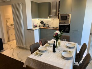 A modern kitchen with grey cabinets, a built-in microwave, and a dining area with a table set for six. - Zagosta apartment in Verbania with balcony (Verbania)