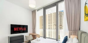 A hotel room with a large window, a flat-screen TV, a bed, a desk, and a chair. - LUX  Contemporary Suite with Full Marina View 6 (Dubai)