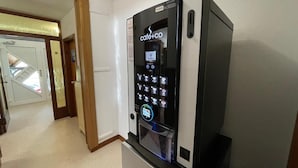 Een compacte, moderne keuken met een ingebouwde koffieapparaat en een koelkast.