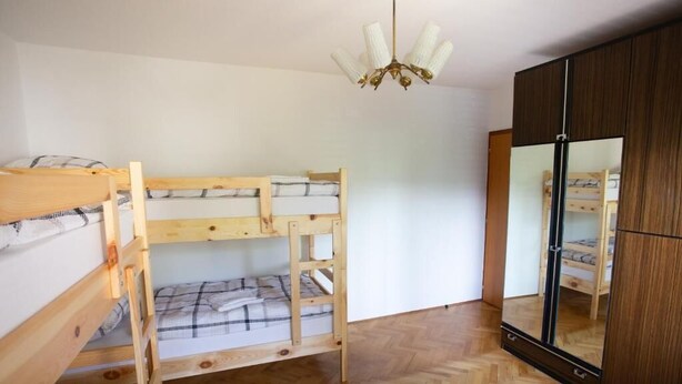 Een slaapkamer met een stapelbed, een houten garderobe en een spiegelkast.