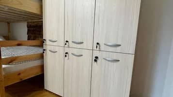 A bunk bed with a wooden headboard, a wardrobe with six doors, and a herringbone-patterned wooden floor.