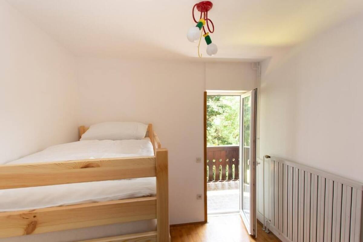 A bedroom with a wooden bunk bed, a white radiator, and a door leading to an outdoor balcony.