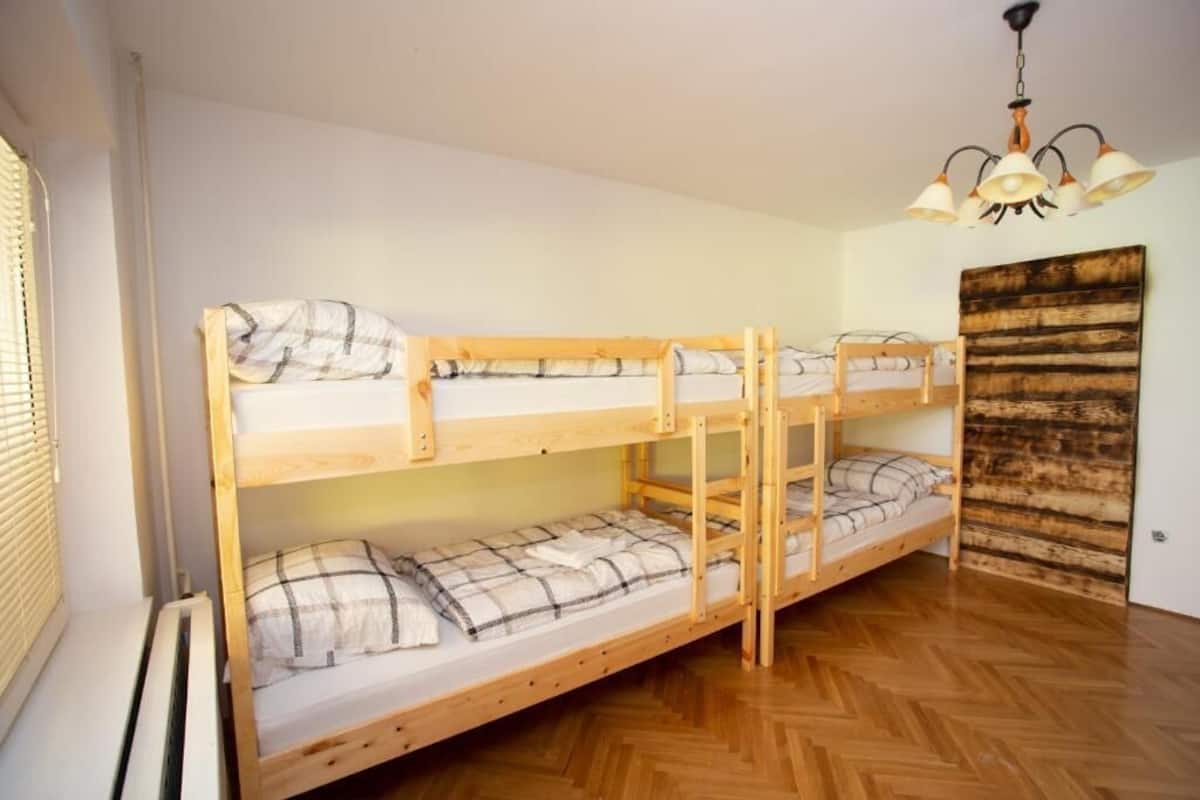 A bunk bed room with a wooden floor, a ceiling light fixture, and a wooden wall panel.